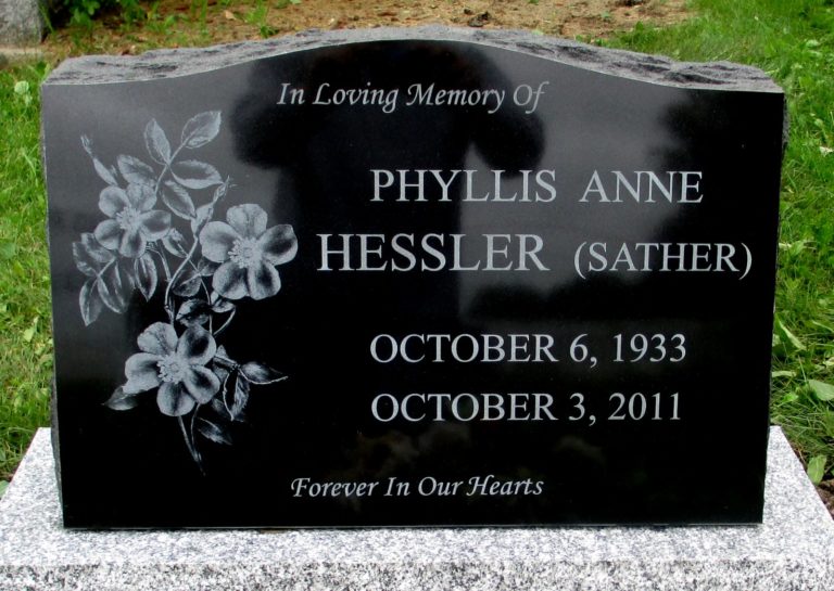Black granite monument with a large set of flowers on the left had side. In loving memory of Phyllis Anne Hessler (Sather) and forever in our heart inscribed on the bottom.