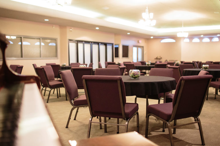 Chapel and Reception Hall on site at Oliver's Funeral Home. Chairs around round tables with round glass vase centerpieces in the center of each table.