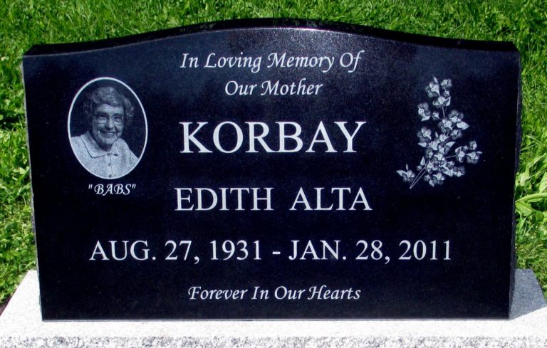 Granite monument in loving memory of our mother. There is a portrait of her on the left hand side and flowers on the right on either side of her name and birth date followed by death date.