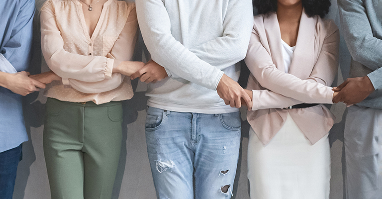 Close up of multiracial business team holding each other's crossed hands, panorama, teamwork concept