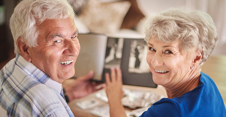 Cheerful senior couple browsing album with their photographs