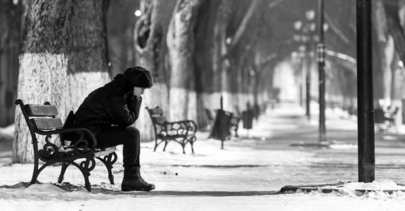 Sad woman sitting on a bench in winter time.